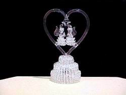 in the blown glass Angel wedding cake top with 2 knitted glass Angels inside a solid glass heart with wedding bells on a three tier knitted glass base.